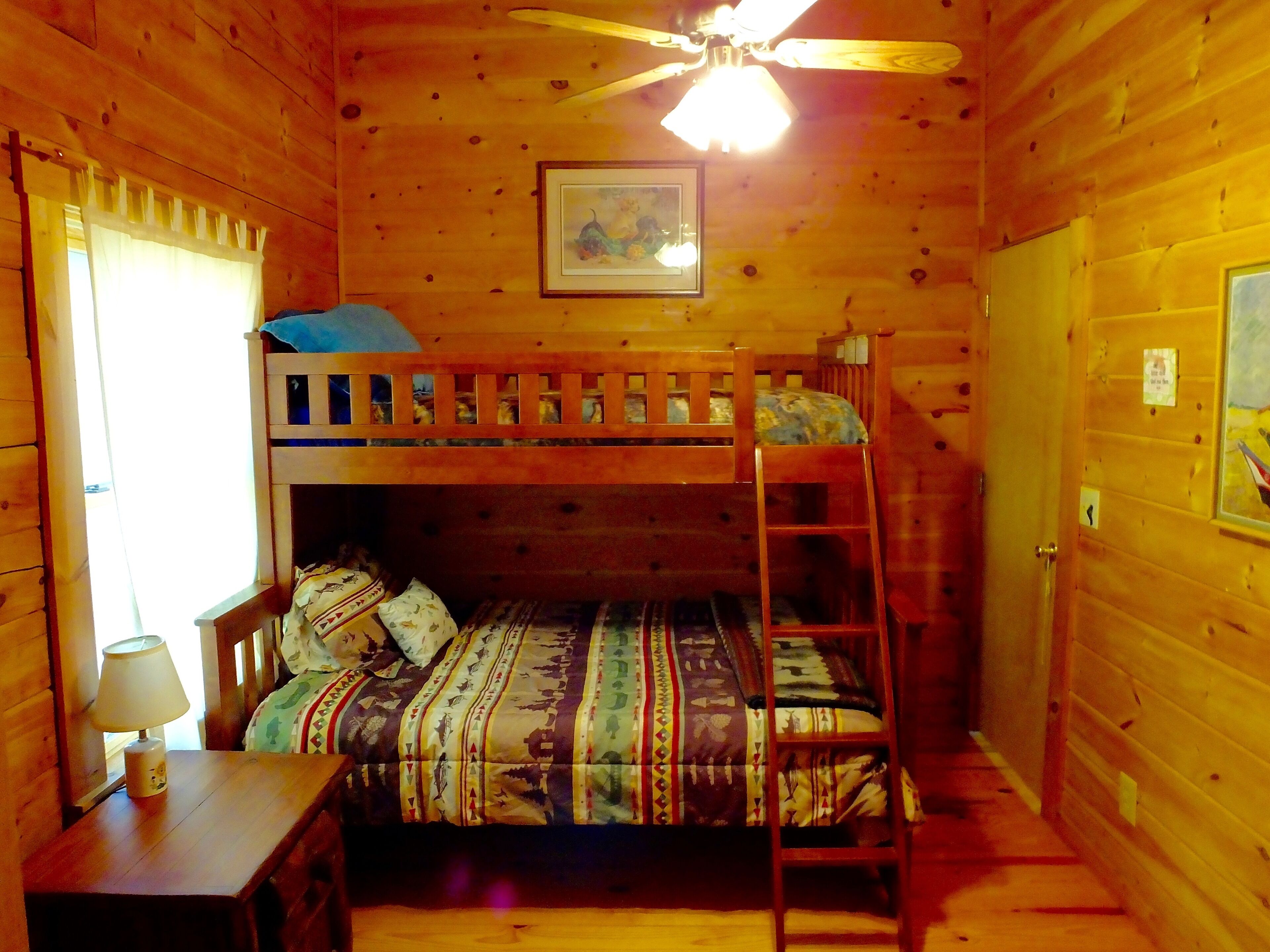 Eine Hütte mit Etagenbett, Schreibtisch mit Lampe und Deckenventilator.
