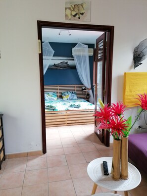 Una habitación con una cama, una mesita con un florero y un cuadro en la pared.