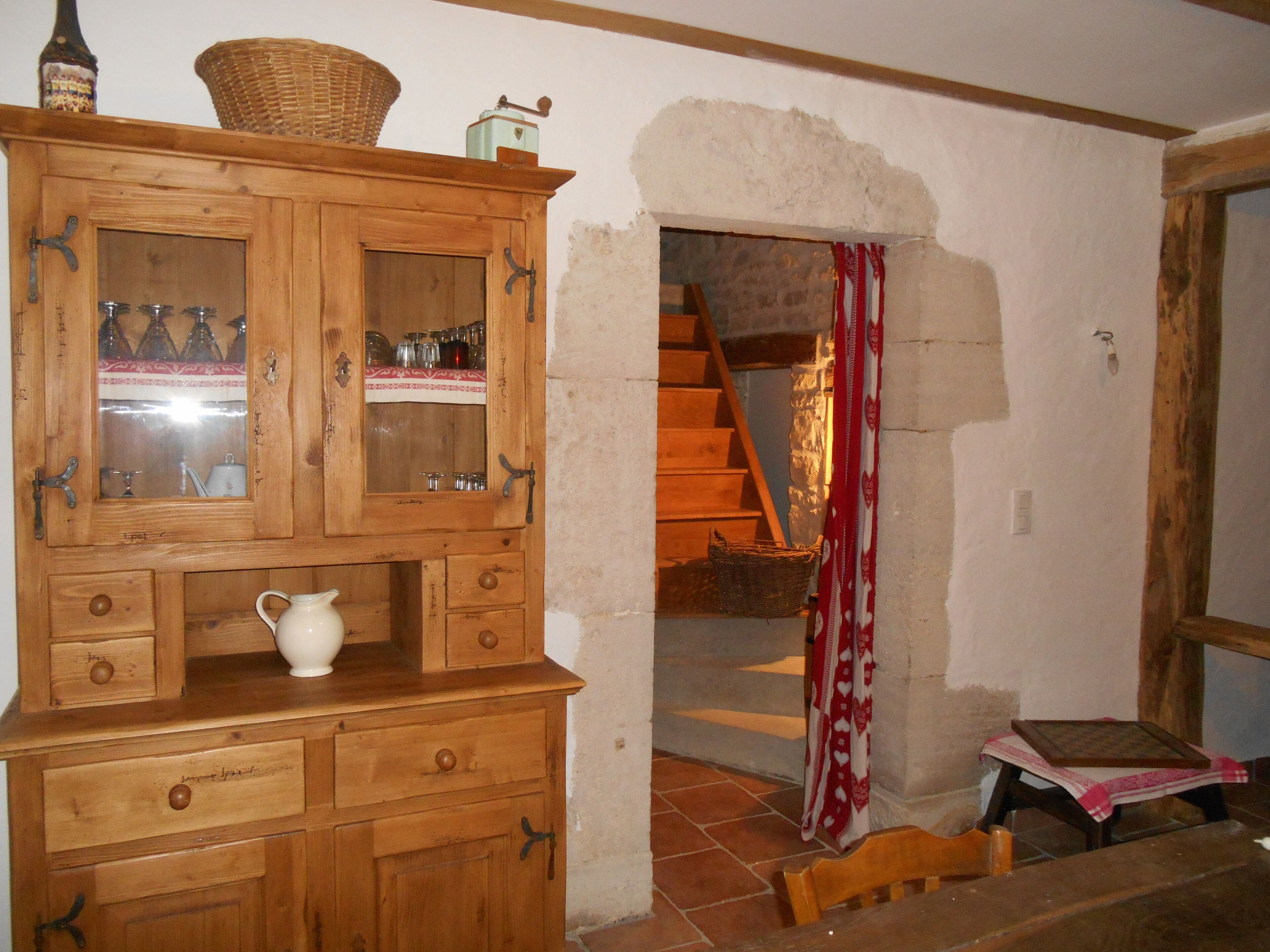 Ein Holzkabinent mit Glastüren, eine weiße Kanne und ein Korbwägelchen darauf.