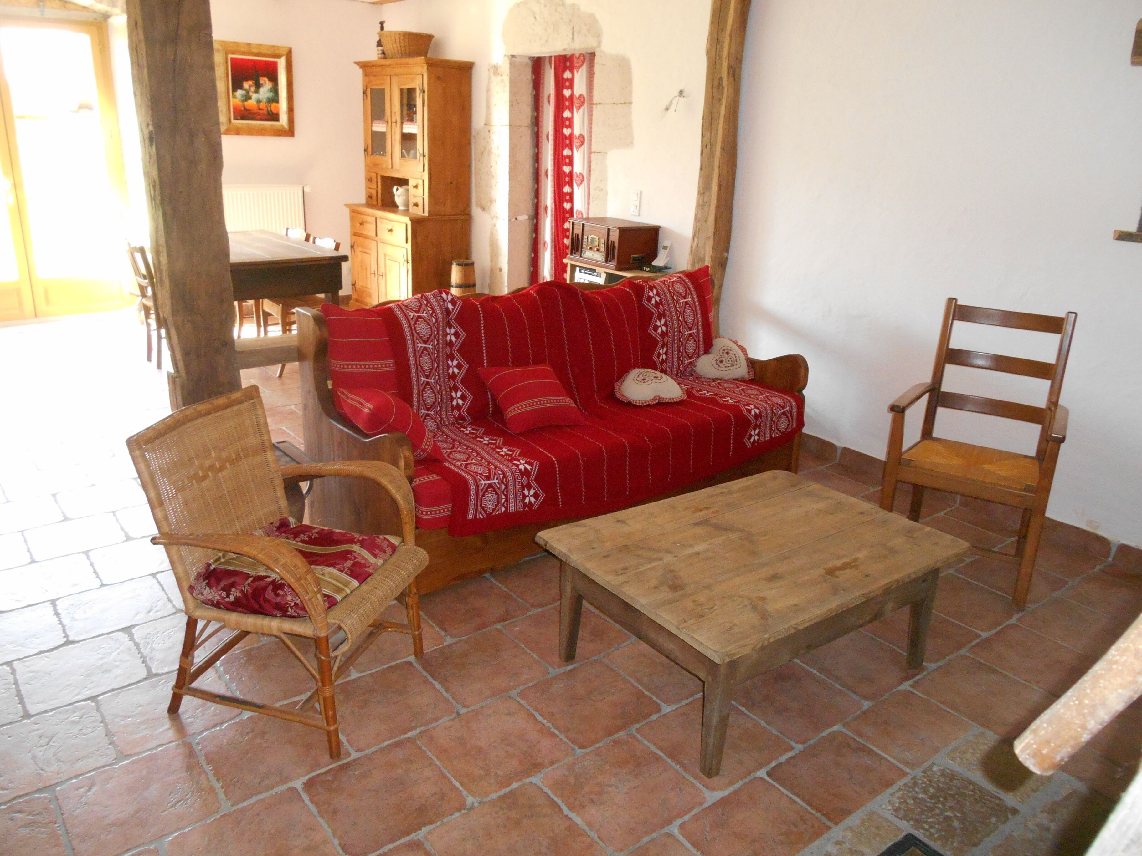 Una sala de estar acogedora con un sofá rojo, sillones de madera y una mesa de centro de madera.