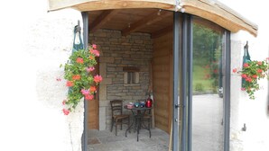 Un espacio al aire libre acogedor con paredes de piedra y techo de madera, con una mesa y sillas.