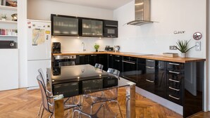 Een moderne keuken met zwarte kastjes, een houten aanrecht en een glazen eettafel.