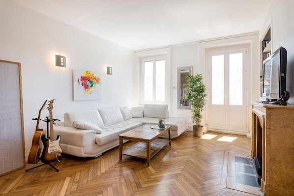 A modern living room with a sectional sofa, a coffee table, a fireplace, and a television.
