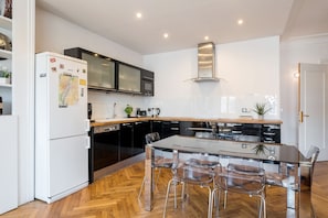 A modern kitchen with a central island, black cabinets, and a stainless steel range hood.