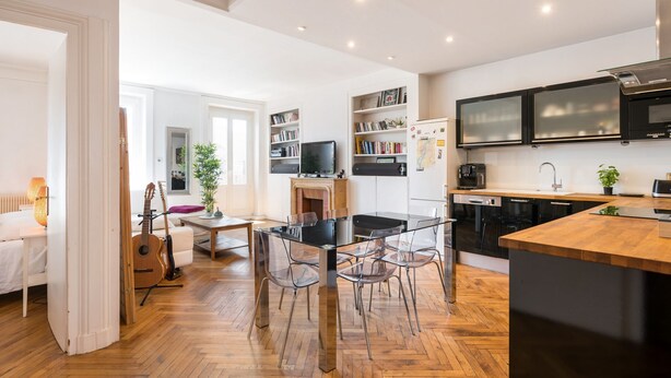Een moderne keuken met een eethoek, houten vloeren en inbouwapparatuur.