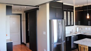 A modern kitchen with stainless steel appliances, black cabinets, and a wooden dining table.