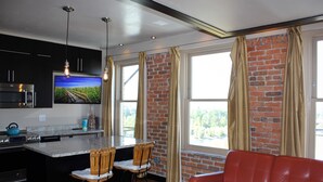 A modern kitchen with a central island, bar stools, and a red leather sofa.