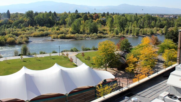 A riverside view with a bridge, trees, and mountains in the background.