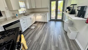 A modern kitchen with white cabinets, a stove, and a coffee maker.