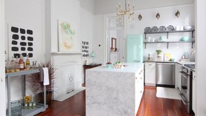 A modern kitchen with a marble island, stainless steel appliances, and a pendant light.