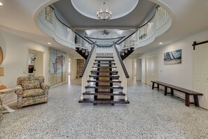 Stunning central staircase with a patterned wall and elegant chandelier.