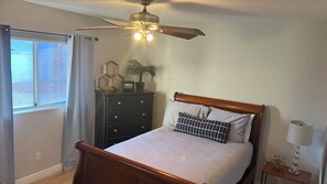 A bedroom with a bed, a dresser, a ceiling fan, a window with curtains, and a bedside lamp. - Lake House to RELAX and Have FUN!!  FREE Wi-Fi. (Lake Havasu City)