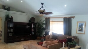 Ein Wohnzimmer mit Sofa, Fernsehtisch und Deckenventilator.