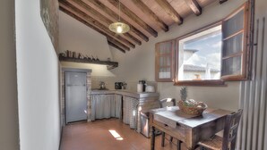 A kitchen with a wooden ceiling, a window with wooden shutters, a refrigerator, and a dining table with chairs. - Tuscan Apart for 4/5 persons, WIFI, AIR-CO, SW-POOL, all comforts in the country (Montespertoli)