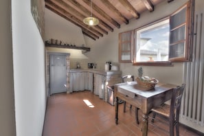 A kitchen with a wooden ceiling, a window with wooden shutters, a refrigerator, and a dining table with chairs. - Tuscan Apart for 4/5 persons, WIFI, AIR-CO, SW-POOL, all comforts in the country (Montespertoli)