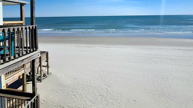 A beach with a wooden structure, possibly a lifeguard tower, and a clear view of the ocean.