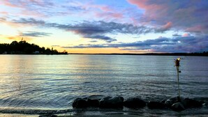 A calm lake at sunset with a clear sky and a distant shoreline.