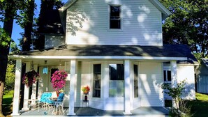 A white two-story house with a front porch, a small window, and a door.