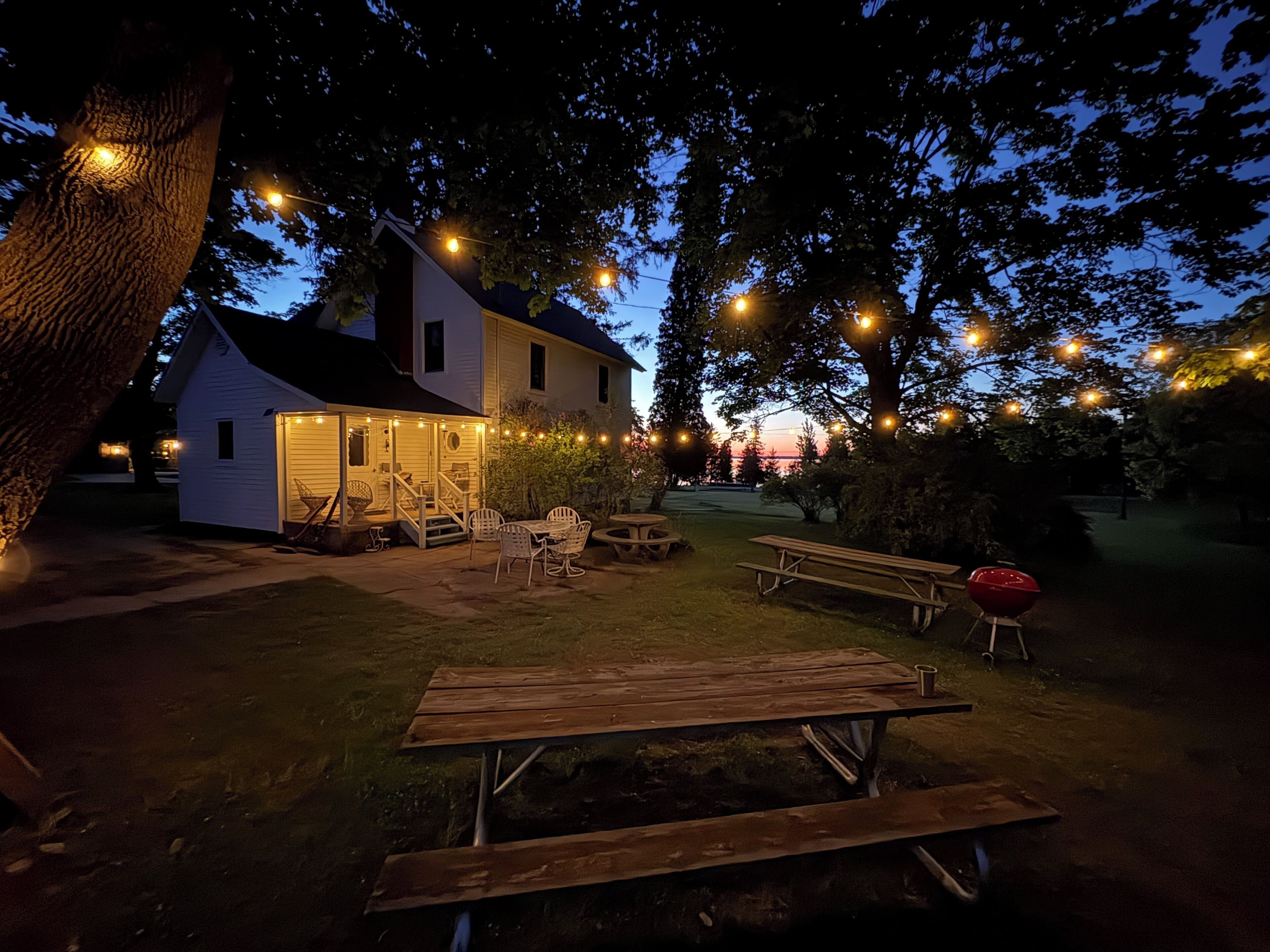 Una casa con porche, mobiliario exterior e iluminacion con luces colgantes.