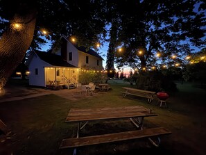 Une maison avec un porche, des sièges d’extérieur et des guirlandes lumineuses.