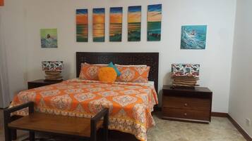 A bedroom with a bed, nightstands, a chair, and artwork on the walls.