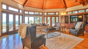 A spacious living room with a high ceiling, large windows, a fireplace, and a television. - Breathtaking View with an Indoor Pool (bluemont)