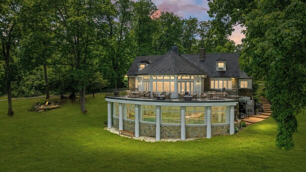 A two-story house with a covered patio and a stone fireplace. - Breathtaking View with an Indoor Pool (bluemont)