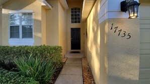 A house with a number 1735 on the wall, a black door, and a pathway leading to the entrance. - FREE Pool/Spa heat - AMAZING  REVIEWS! Be My Guest!!  (Clermont)