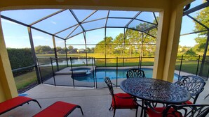 A covered patio with a pool, red chairs, and a table. - FREE Pool/Spa heat - AMAZING  REVIEWS! Be My Guest!!  (Clermont)