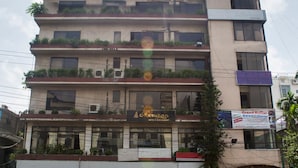 A multi-story building with a restaurant on the ground floor, multiple balconies with plants, and a parked car in front. - Meridian Hotel (Chittagong)