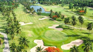 A golf course with sand bunkers, palm trees, and a water body. - Seastar Hotel And Service Apartment (Ban Chang)