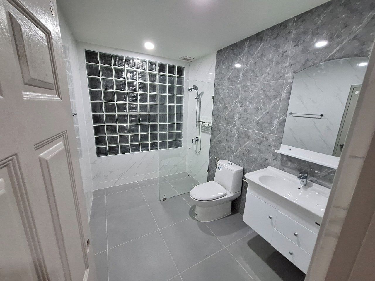 A modern bathroom with a toilet, sink, and shower.