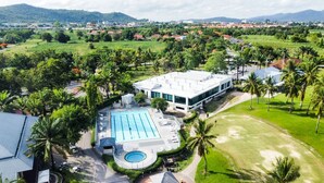 An aerial view of a resort with a large swimming pool, a tennis court, and lush greenery. - Seastar Hotel And Service Apartment (Ban Chang)