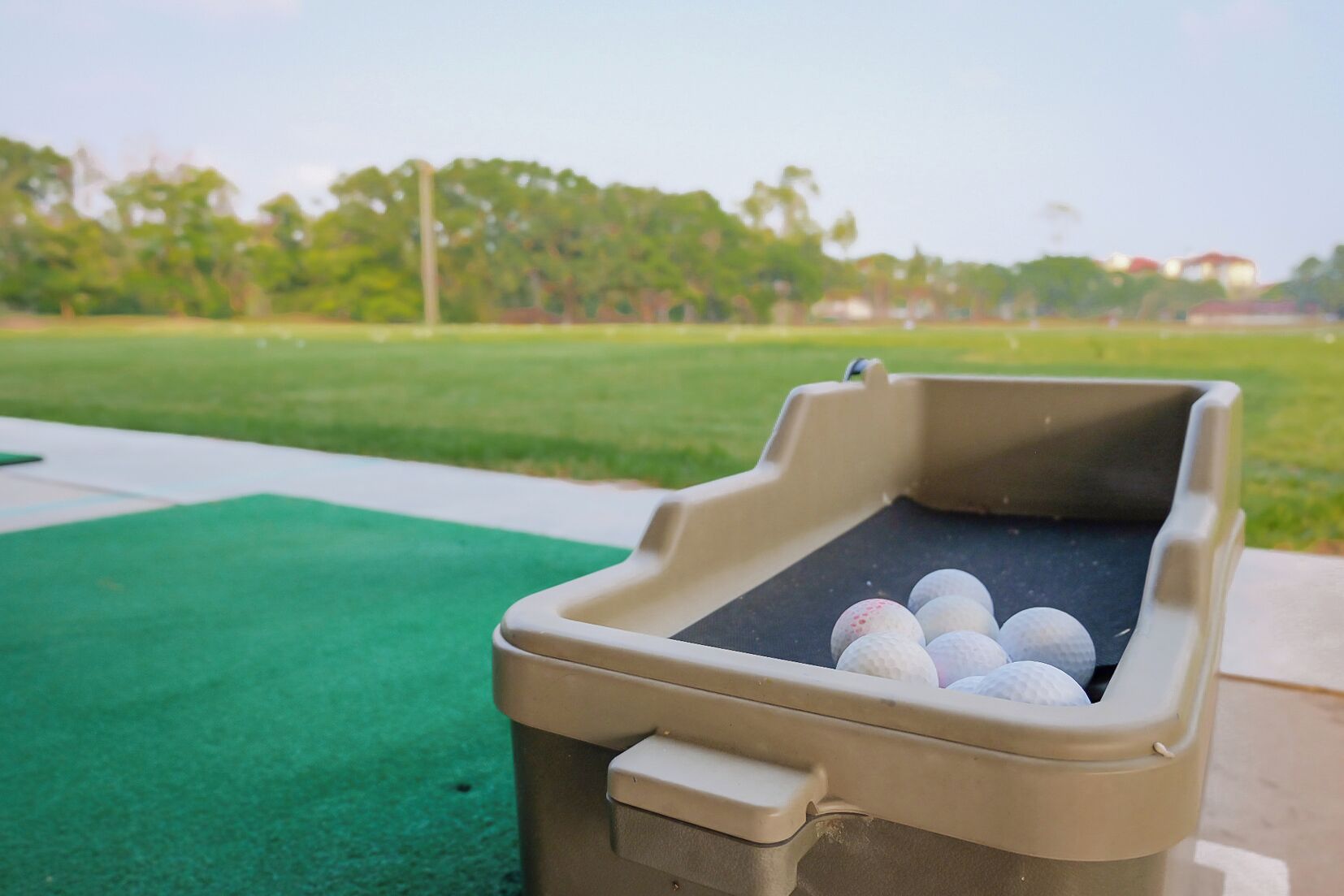 Un carrito de golf portátil con una bandeja que contiene pelotas de golf.