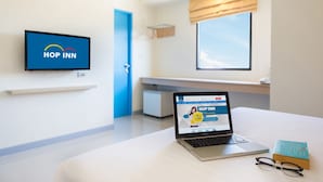A hotel room with a laptop displaying a website, a book, and a pair of glasses on the bed.