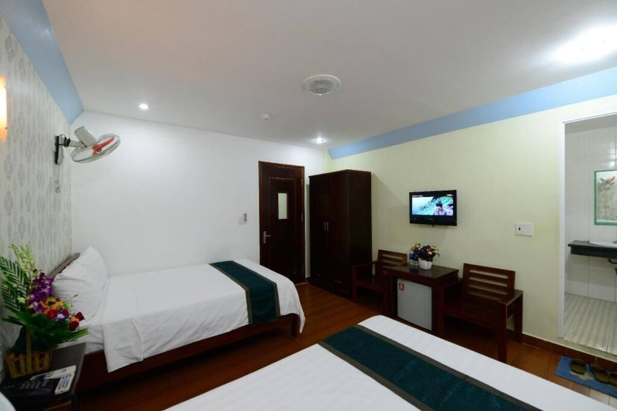 Een hotelkamer met twee bedden, een bureau, een televisie en een kleine badkamer.