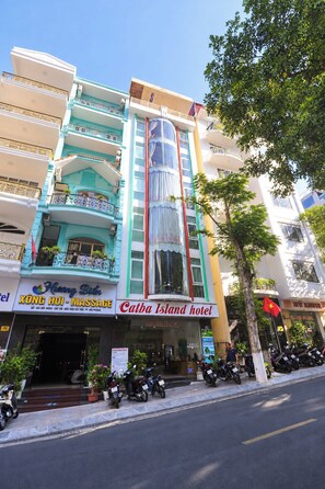 A multi-story hotel with a prominent massage service sign and a flag. - Catba Island Hotel (Hai Phong)