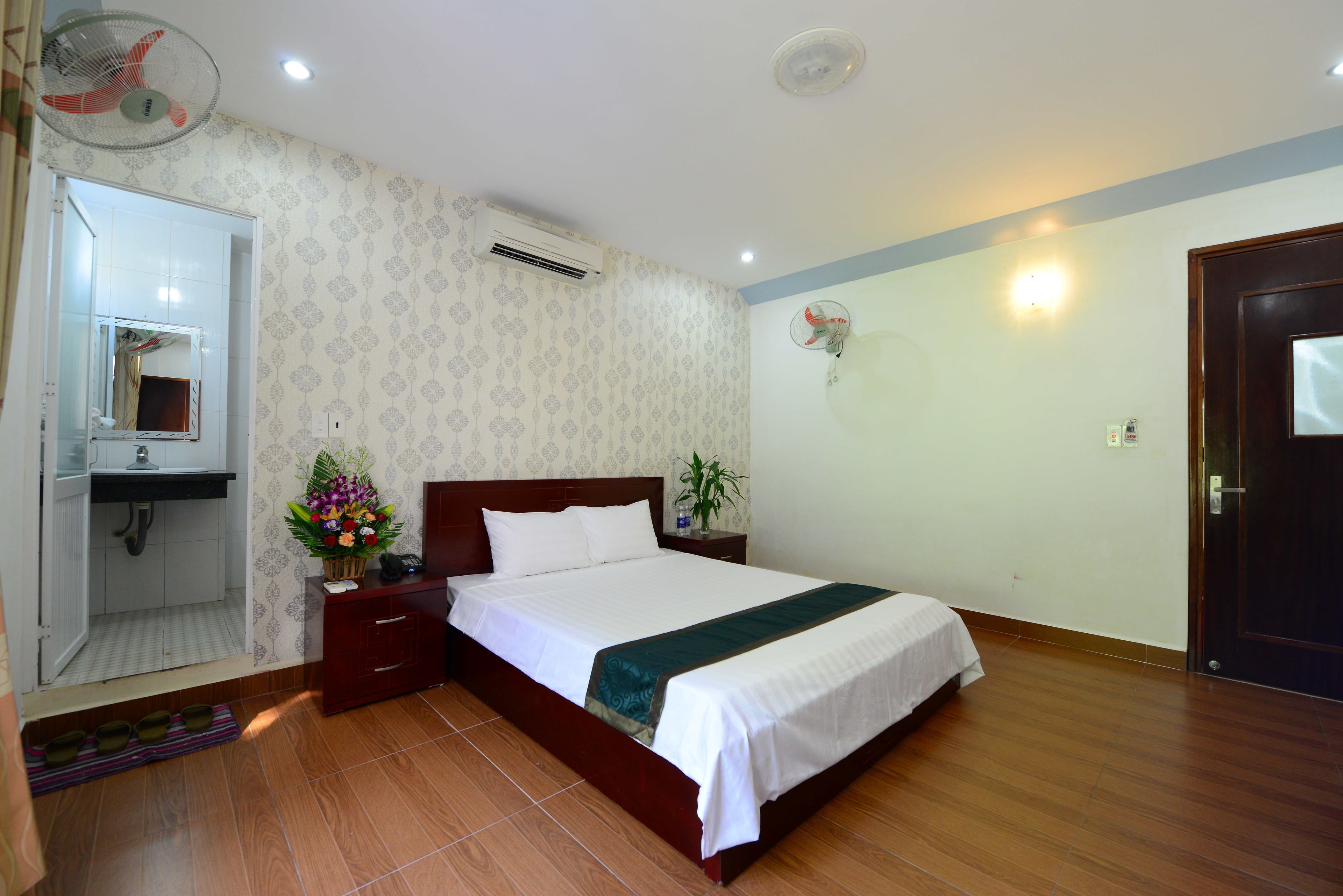 Un dormitorio ordenado con cama, mesita de noche y espejo.