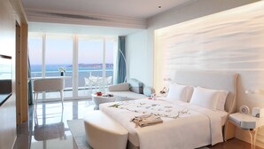 A modern hotel room with a large bed, a seating area with a view of the sea, and a balcony with a table and chairs. - The Mangrove Resort Hotel Sanya (Sanya)