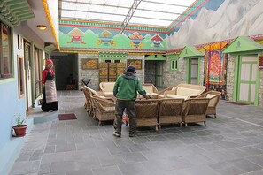A traditional building with a high ceiling, colorful murals, wicker furniture, and stone walls. - Mountain Lodges of Nepal - Thame (Thame)