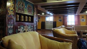 Una habitación con decoración tradicional, que incluye una pared con pinturas coloridas, un sofá y una ventana con cortinas.