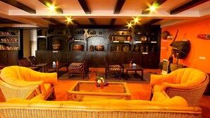Un rincón acogedor con muebles de mimbre, chimenea y estantes con diversos objetos.