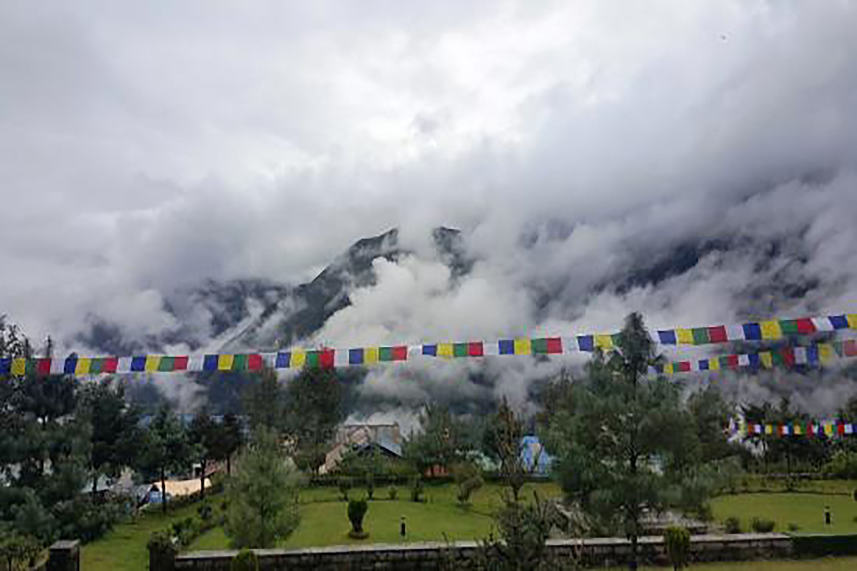 A mountainous landscape with a string of colorful prayer flags in the foreground.