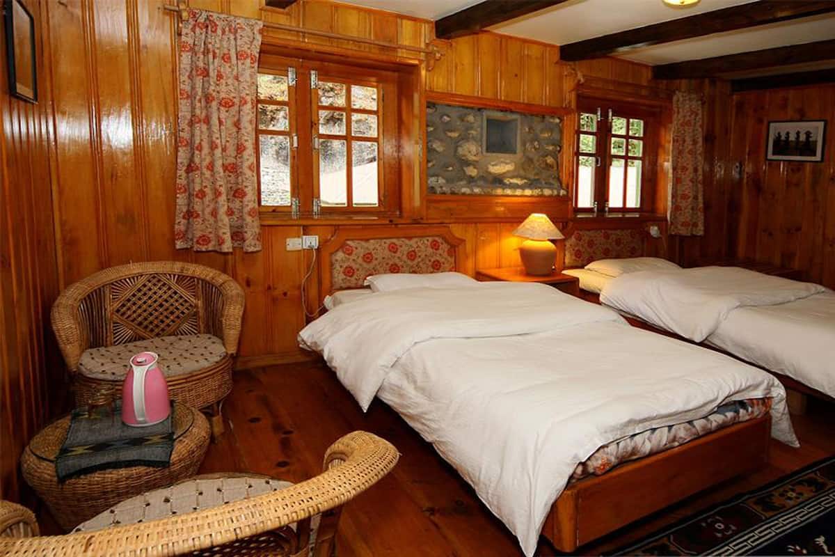 A wooden room with two beds, wicker furniture, and a stone wall.