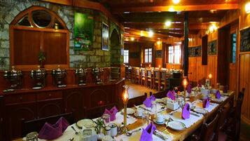 Un restaurante con una larga mesa de comedor dispuesta para una comida, paredes de madera y detalles de piedra.