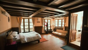 A room with a bed, a bench, and a door leading to another room.