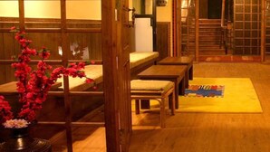 A traditional Japanese room with tatami flooring, low wooden tables, and a sliding door.