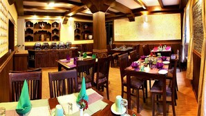 A restaurant with wooden beams, a bar area, and multiple dining tables set for guests.