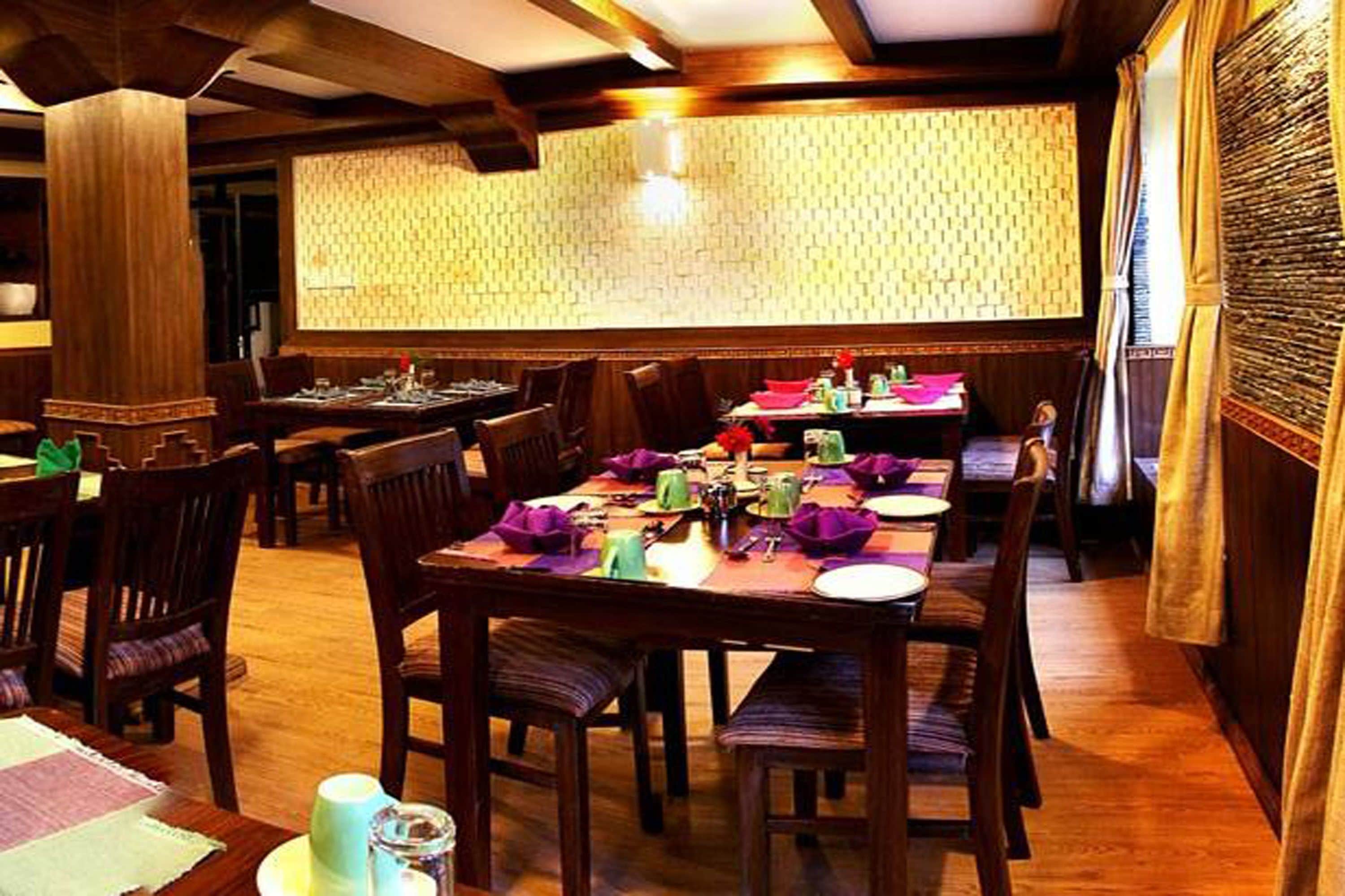 Un restaurant doté de meubles en bois, d’un mur orné de motifs et d’une ambiance chaleureuse.
