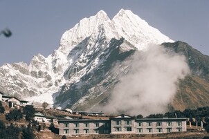 Montanha com pico nevado e um edifício com várias janelas em primeiro plano.